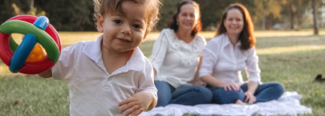 A joyful family enjoying a picnic in the park with a playful toddler in the foreground.
